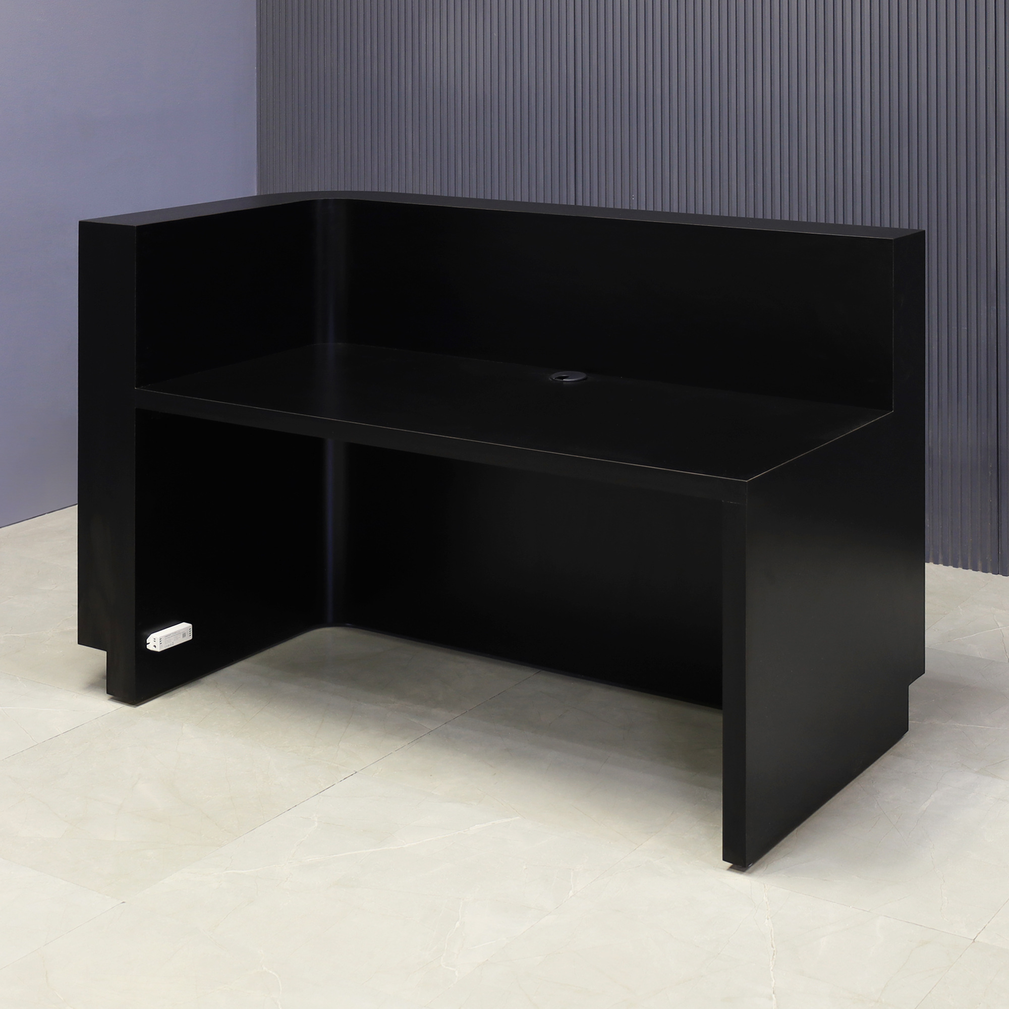 60-inch Nola L-Shape Custom Reception Desk with the l-panel on the right side. The main desk is covered in black traceless tambour, the workspace and toe-kick in black matte laminate, and comes with warm white LED.