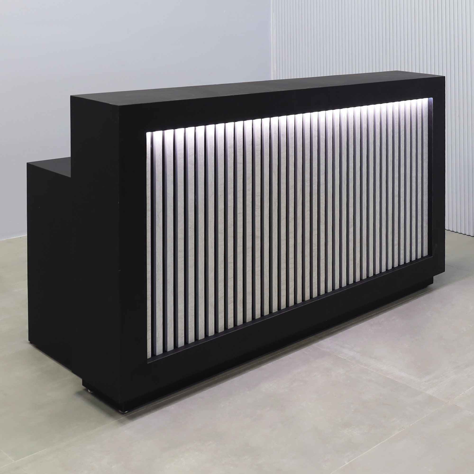 72-inch Vegas Designer Custom reception Desk with Black Traceless laminate main desk. Spanish Limestone slats front panel, warm white LED.