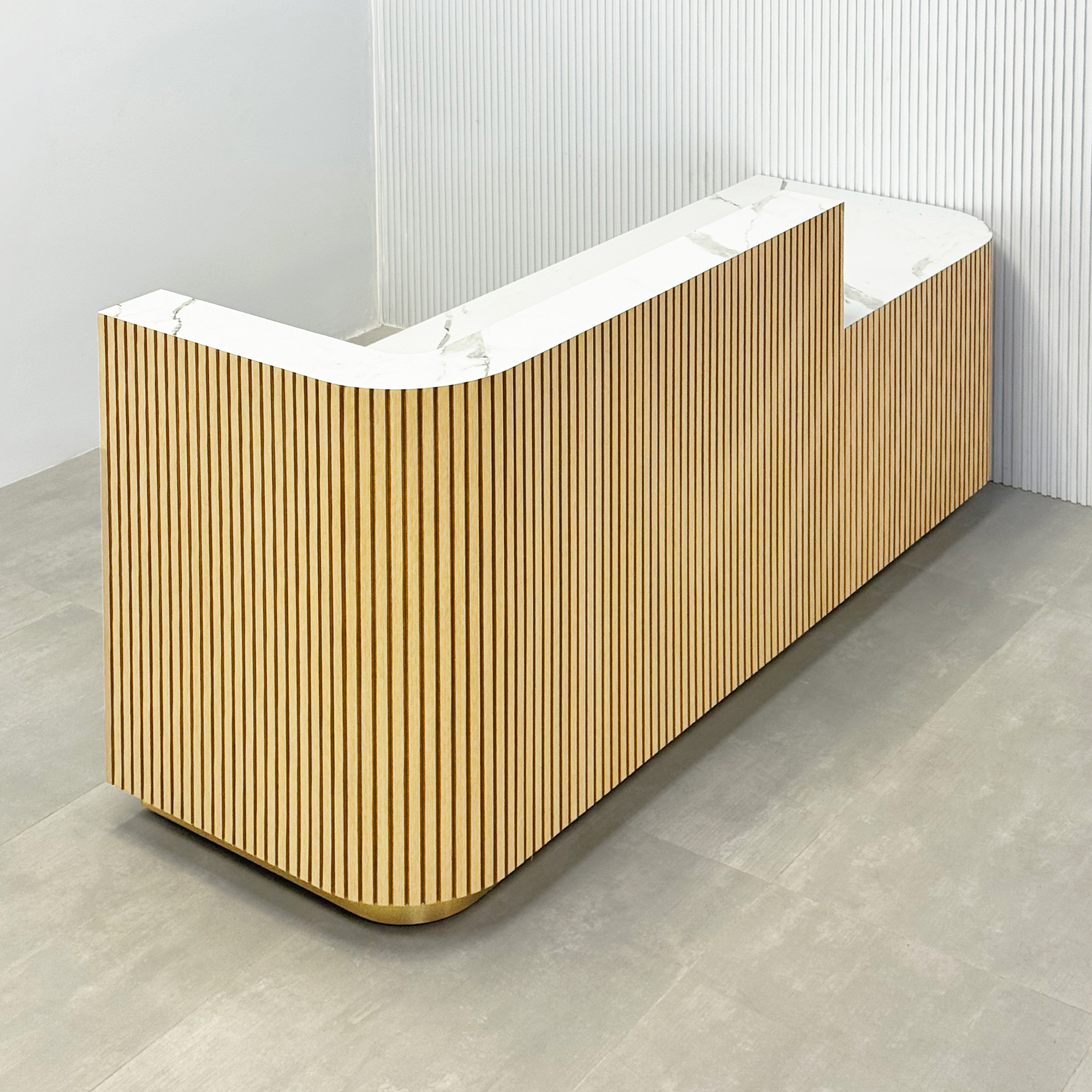 90-inch Nola ADA Reception Desk with White Oak tambour desk, Calcutta stone PVC laminate workspace & storage, and gold aluminum toe-kick.