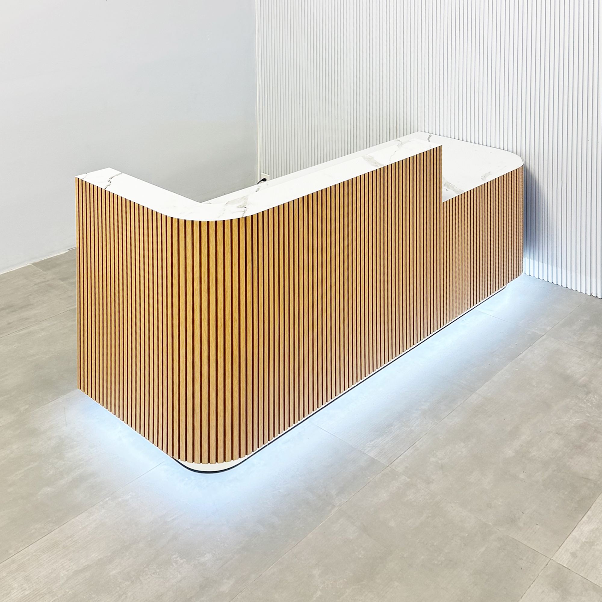 90-inch Nola Low Counter Reception Desk with white oak tambour desk, calcutta stone PVC laminate workspace & storage, gold aluminum toe-kick, and white LED.